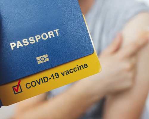 Coronavirus Vaccination passport concept. Hand in medical glove holding passport with covid-19 vaccine certificate on background of   man with coronavirus vaccine injection. Travel due Covid-19