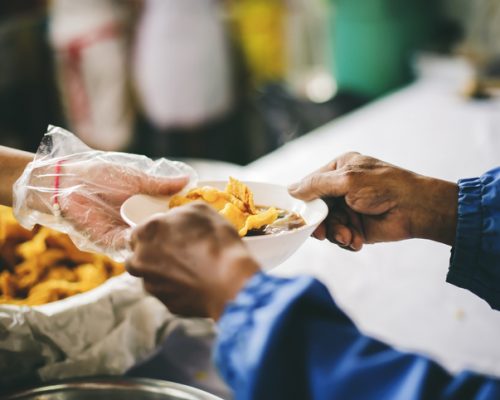 Volunteers scooping the food to share with the needy : concept of providing free food to homeless people.